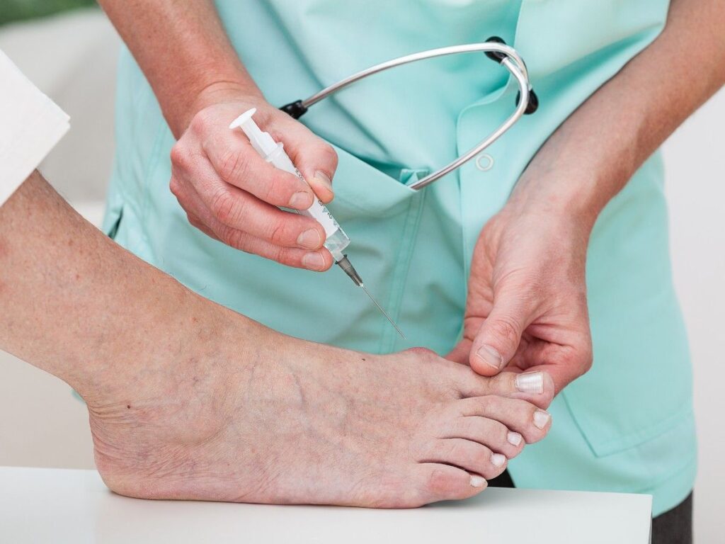 A doctor injecting a patient’s bunion in preparation for surgery.
