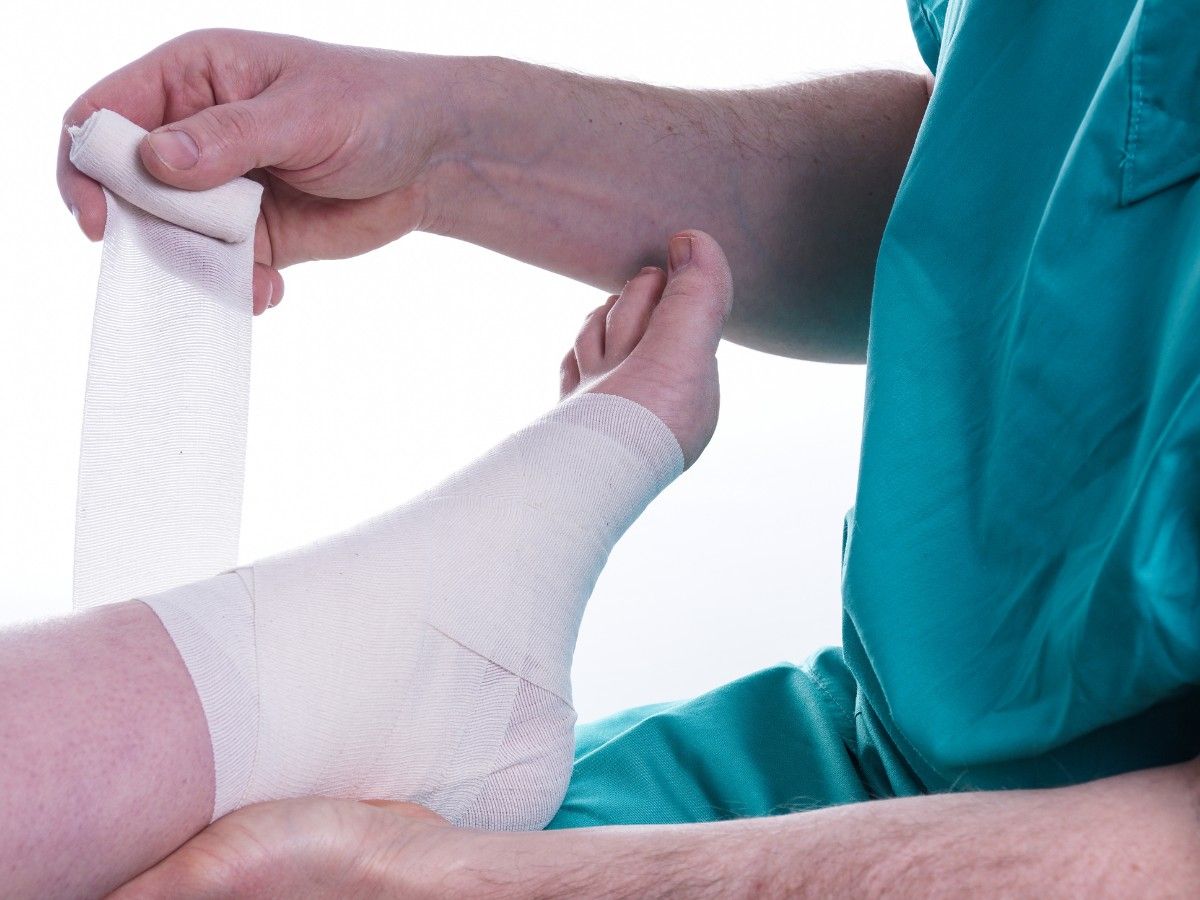 A foot doctor in Silverglen Estates wrapping a patient’s foot with a medical bandage, providing support and treatment for a foot or ankle injury.