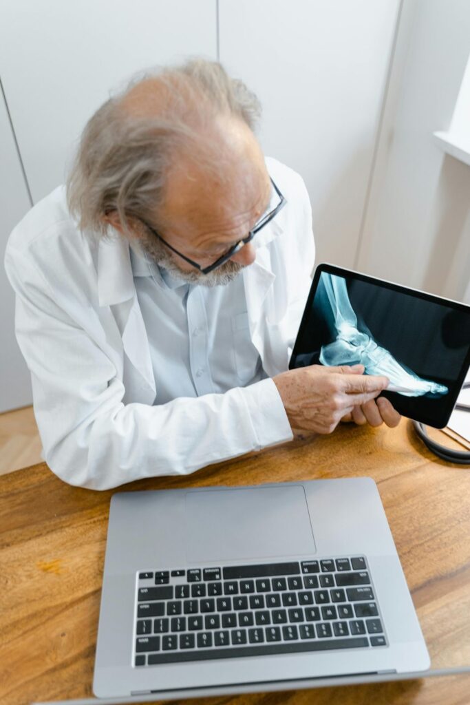 An expert podiatrist shows a patient a foot X-ray on a tablet, a service offered at urgent care for foot pain in Houston.