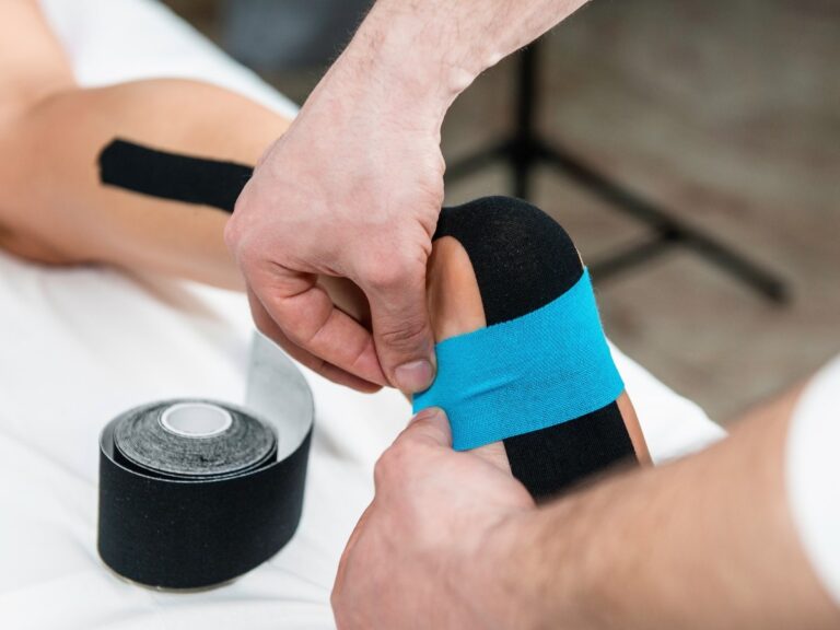 A Medicare podiatrist taping a patient’s heel to relieve pain.