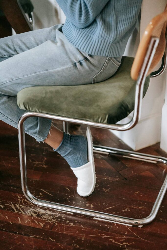 A woman sits down after a long day in heels, a common cause of heel pain that may require urgent care in Houston.