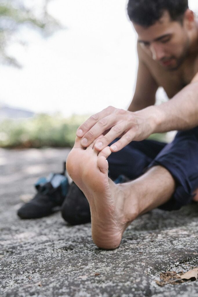An athlete stretches his foot to relieve pain, a sign that he may need a same-day podiatrist in Houston.
