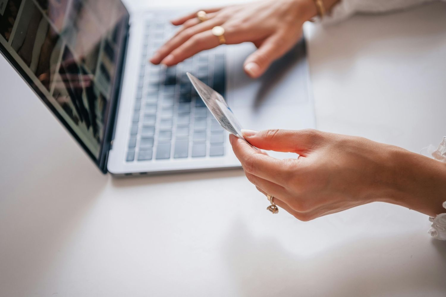 Woman holding Medicare card while typing on laptop to schedule podiatrist appointment in Cypress, highlighting seamless online booking for covered foot health services.