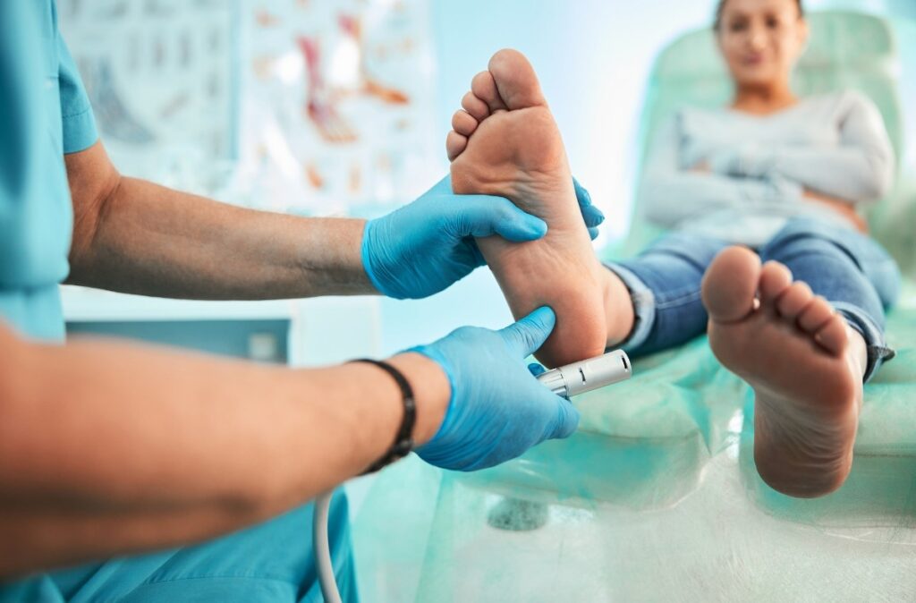 Foot specialist doctor Houston uses handheld device to assess foot health and diagnose conditions in clinical setting.