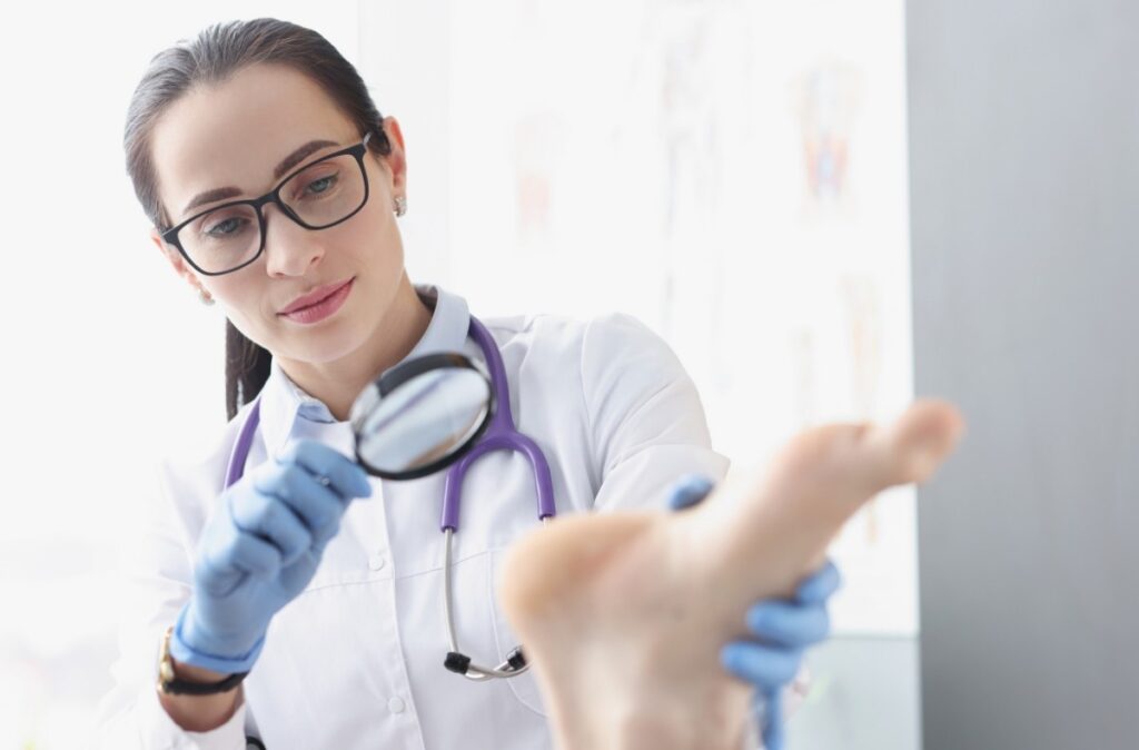 Foot specialist doctor Houston performs detailed sole exam using magnifying glass to diagnose skin or foot conditions.