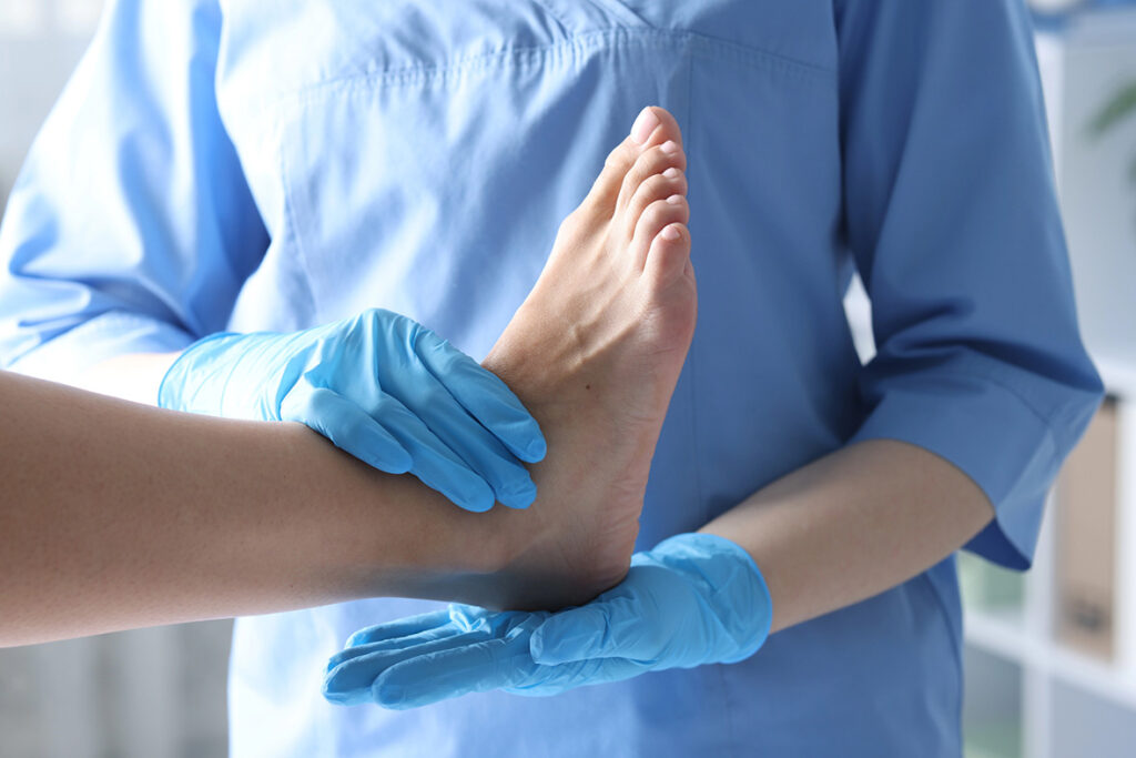 Foot And Ankle Doctor Cypress examining patient’s foot with blue gloves, hands-on ankle assessment in modern clinic