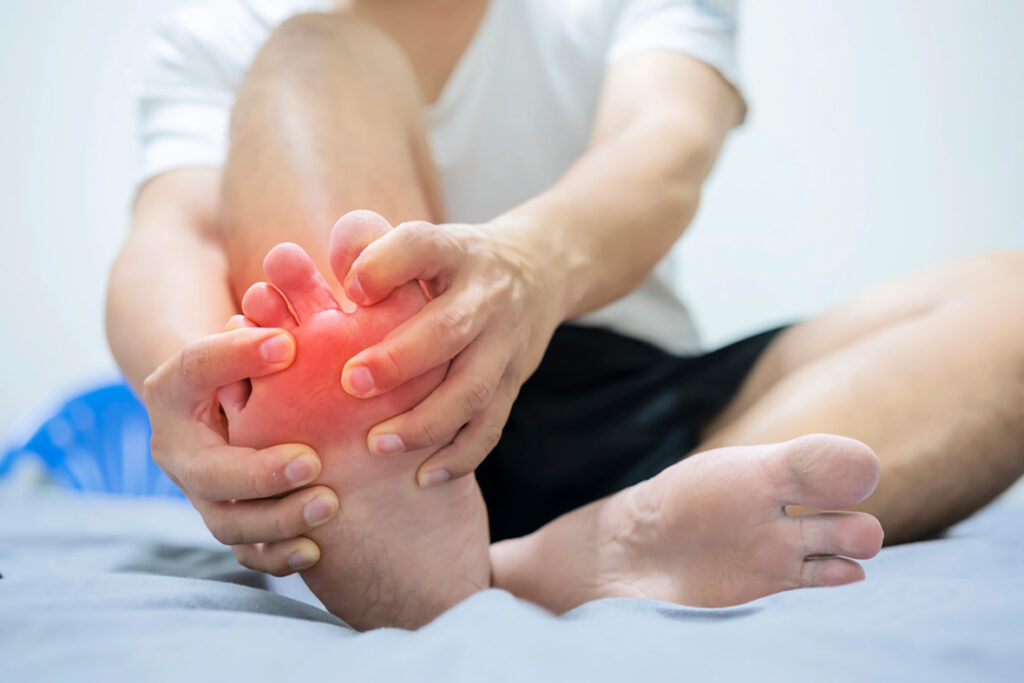 Holding right foot with red, inflamed toes and forefoot, showing acute pain and swelling — Foot Doctor Cypress care