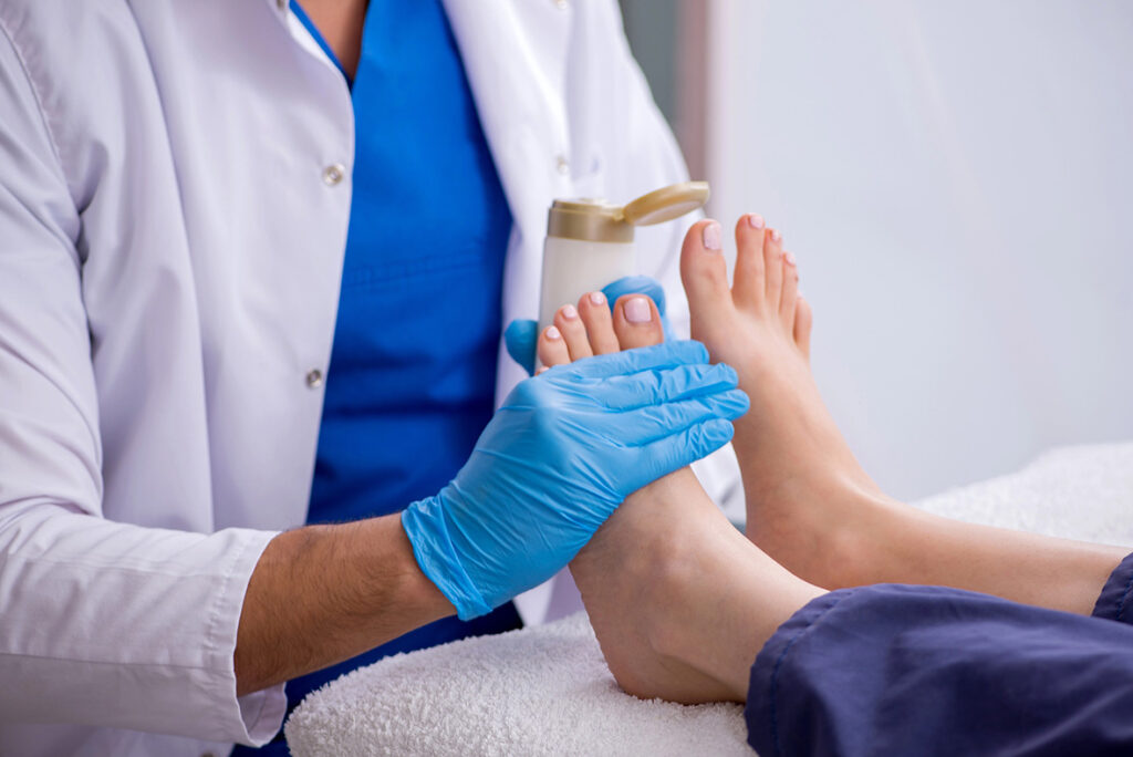 DPM Doctor Cypress provides foot care with gloves and lotion; hygienic podiatry exam with feet on a clean towel in clinic