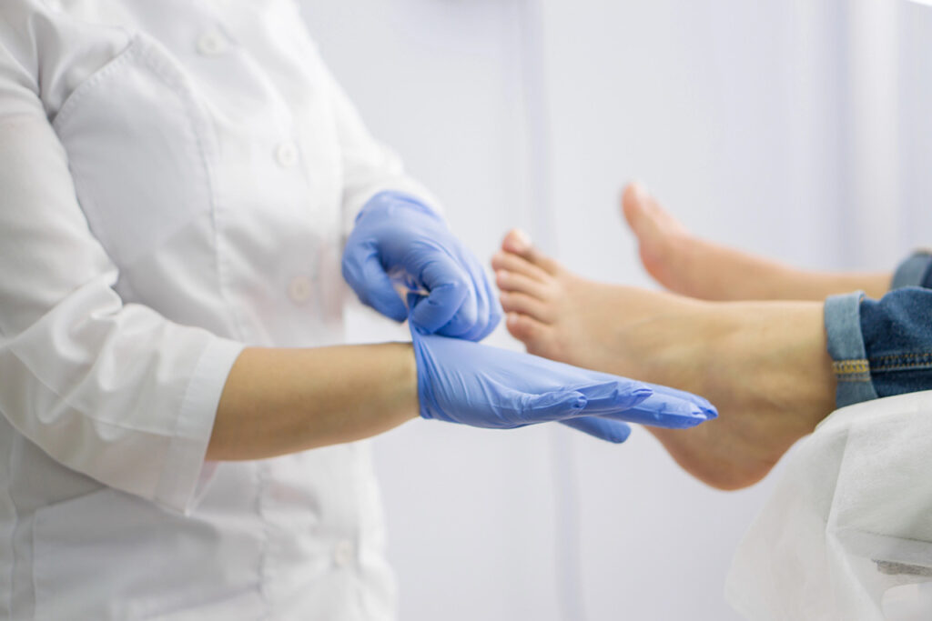 Cash pay podiatrist putting on medical gloves before a sterile foot examination for personalized, out of pocket foot care