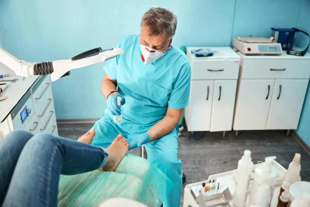 Professional dpm doctor cypress wearing a mask and gloves while performing a clinical foot procedure on a patient.