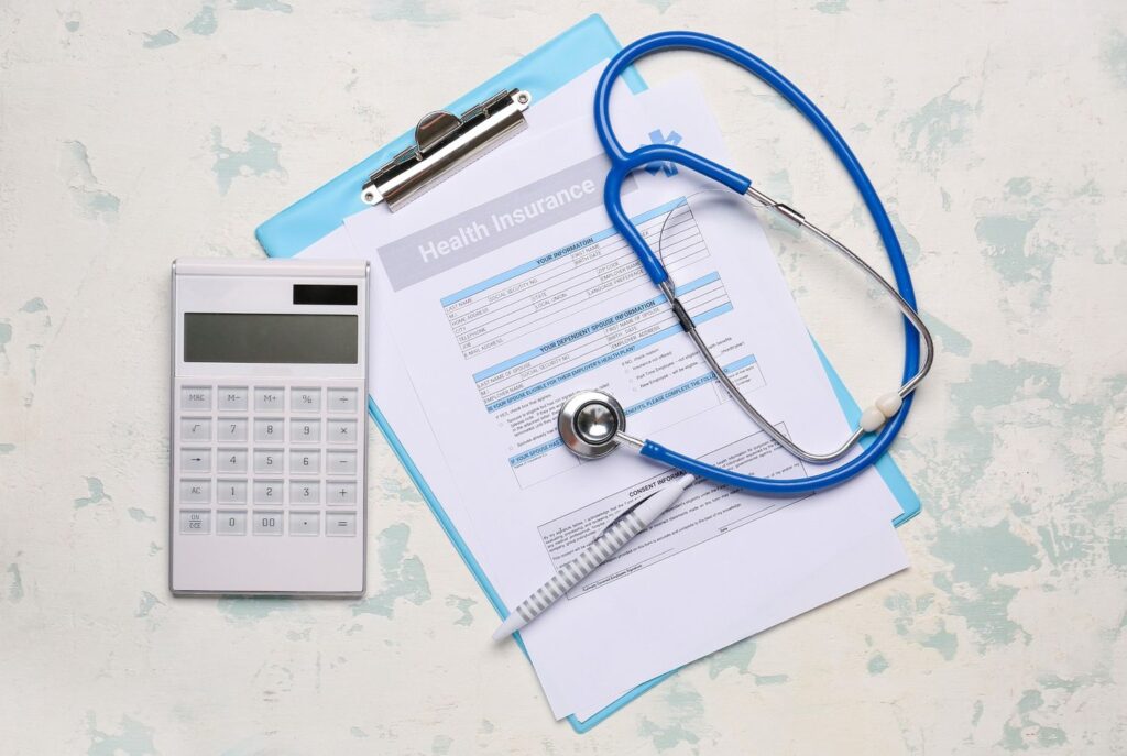 Health insurance form, calculator, and stethoscope on a clipboard, ensuring coverage with a blue cross blue shield podiatrist cypress.