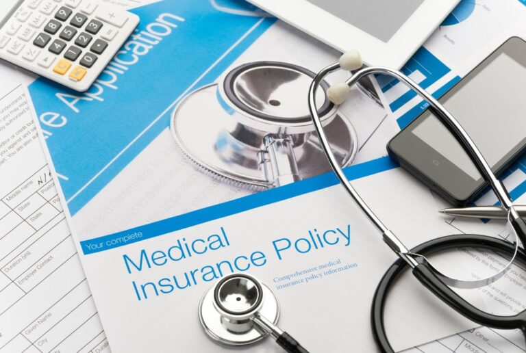 Medical Insurance Policy document next to a stethoscope and calculator; search for a blue cross blue shield podiatrist cypress.