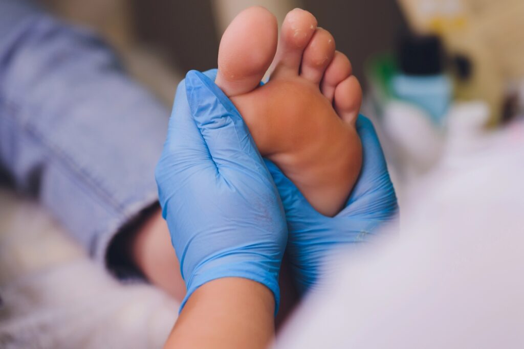 Toe specialist Cypress podiatrist in blue gloves performing a physical foot exam on a patient in a clinic.
