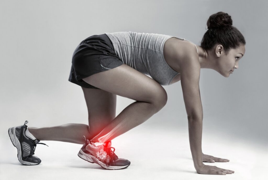 Female athlete in starting position with a highlighted ankle injury that requires a skilled foot specialist doctor.