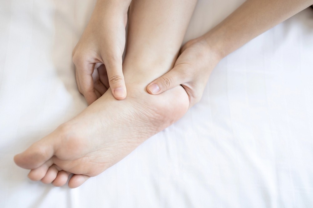 A close-up of hands gently holding and inspecting a person's bare foot, ideal for a heel pain doctor cypress blog