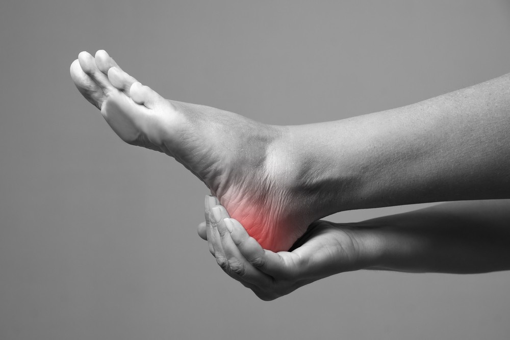 Hands carefully squeeze and perform a manual physical examination on a bare foot for a heel pain doctor cypress blog.